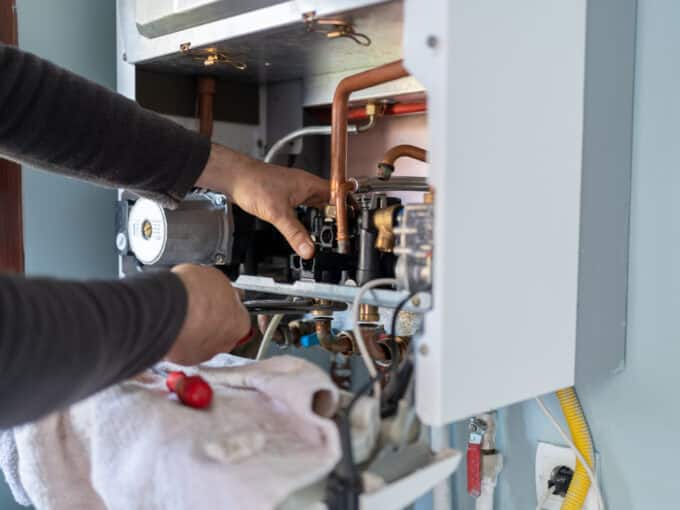 Technician Repairing Natural Gas Combi Boiler At Home